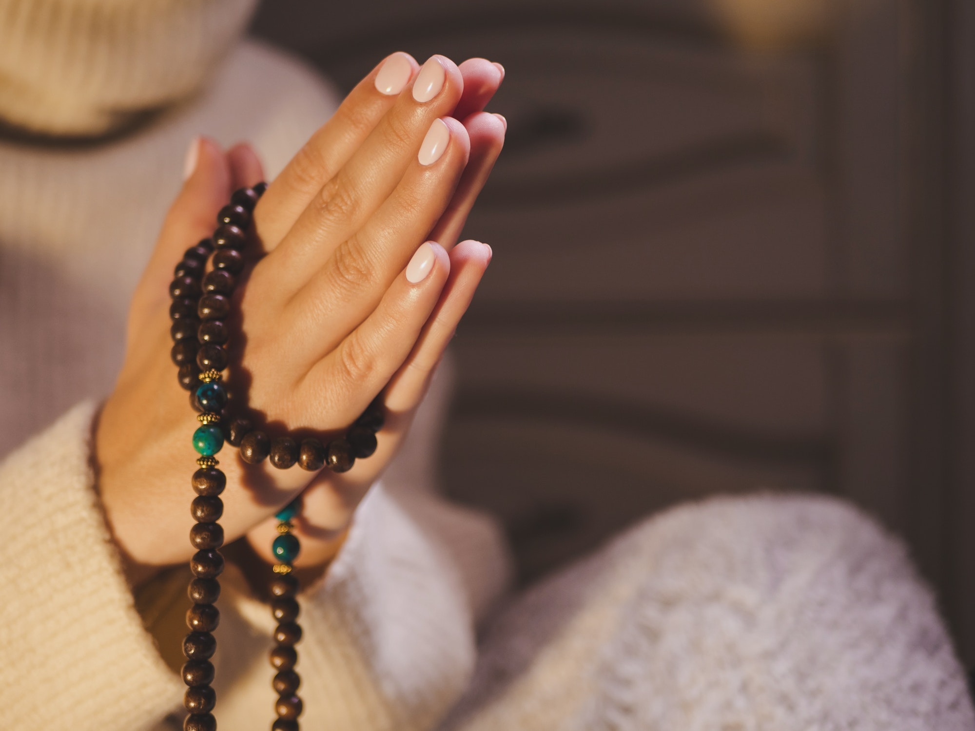 Woman holding mala beads in hand. Counting beads and reading mantra